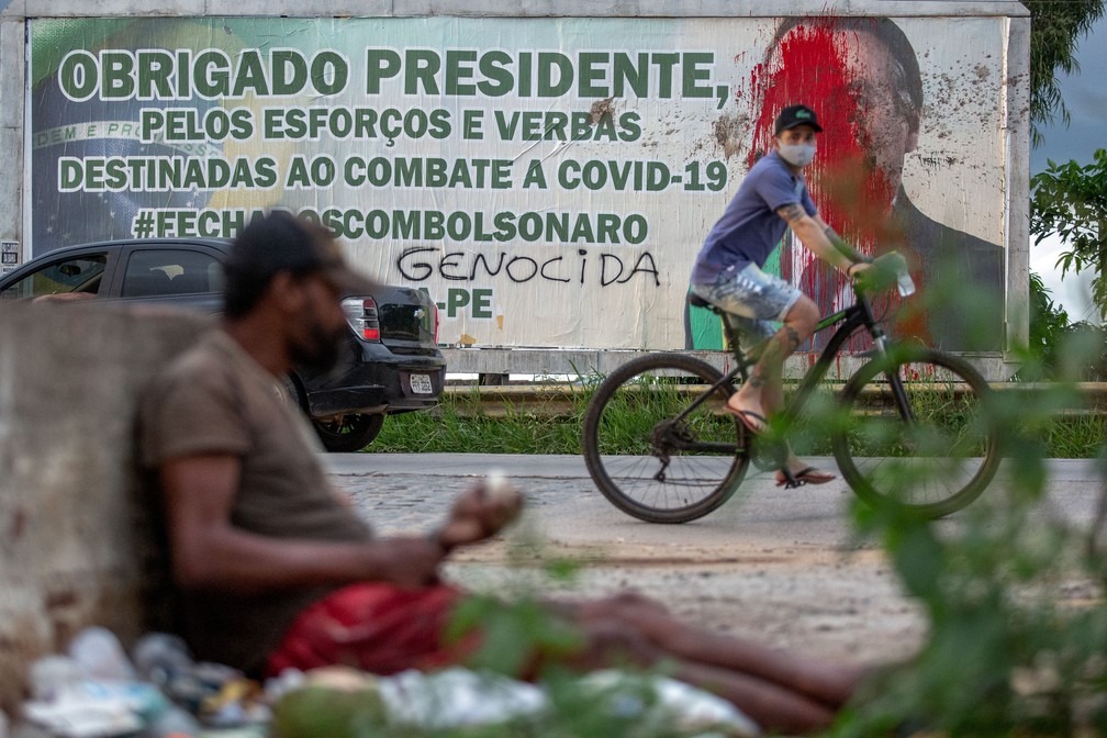 Foto mostra outdoor com texto 'obrigado presidente, pelos esforços e verbas destinadas ao combate a Covid-19 #fechadoscombolsonaro' ao lado do rosto do presidente Jair Bolsonaro coberto de tinta vermelha e pichado com a palavra 'genocida' em Carpina (PE), na Zona da Mata Norte pernambucana, a 45 km de Recife. — Foto: Leo Malafaia/AFP